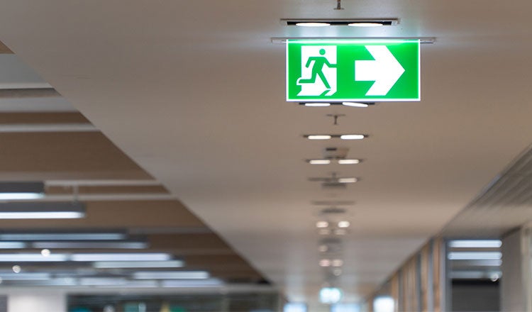 Interior of emergency exit sign shown on the ceiling of a commercial office building.