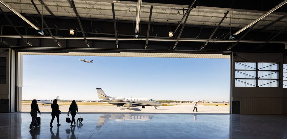 People in a hangar walking towards a private plane 