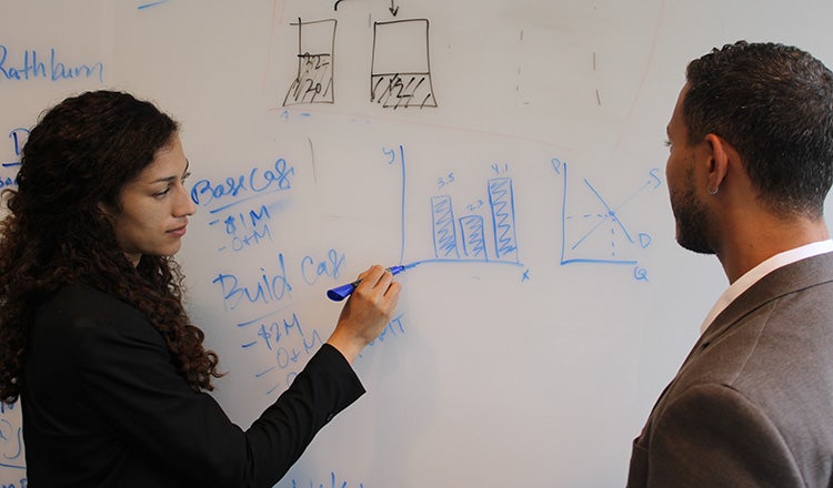 economists drawing chart on whiteboard