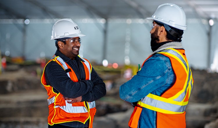 Two people with safety gear talking at job site