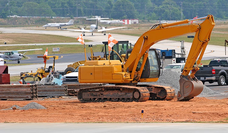 excavator on airfield with planes