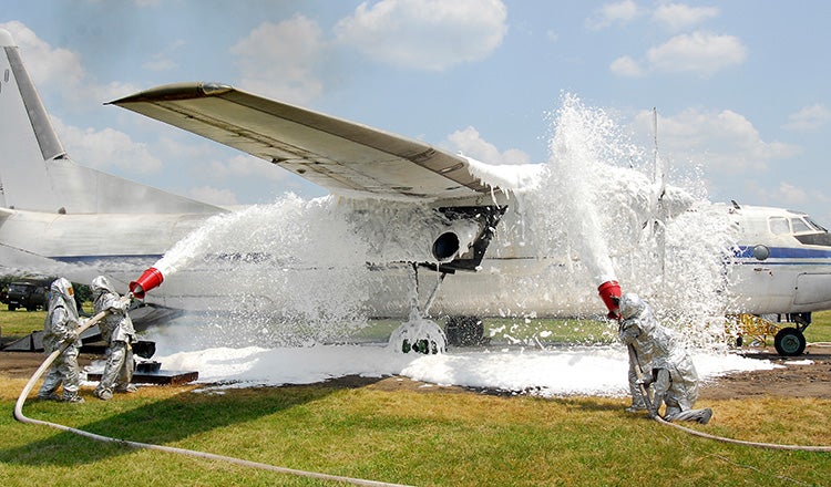 firefighters covering plane with foam