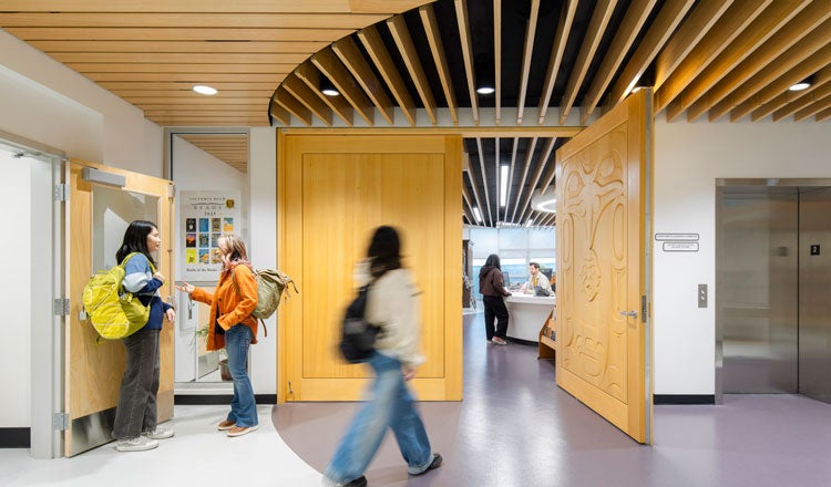 Students in a school hallway, with a student walking through a doorway