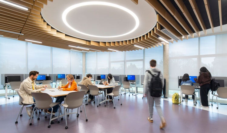 Students working in a classroom with computer and tables spread throughout
